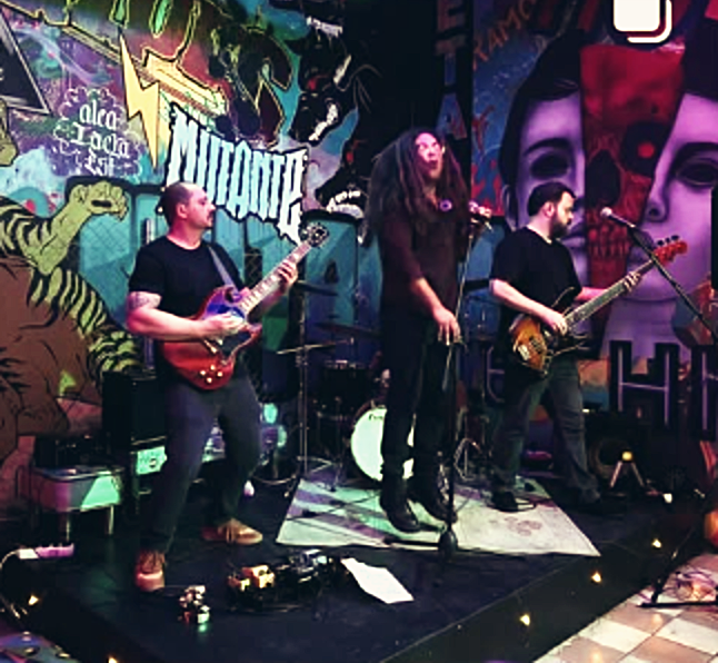 A banda tocando diante de um mural grafitado