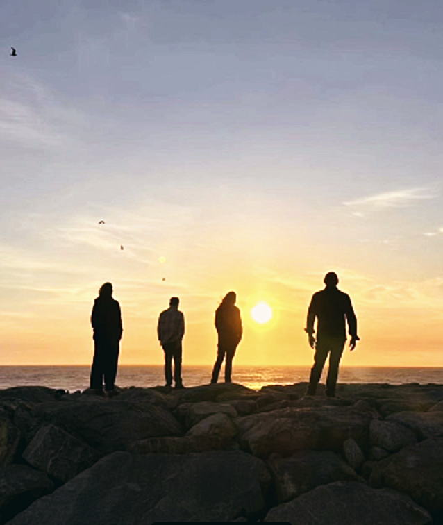 A banda em silhueta ao pôr do sol sobre as pedras
